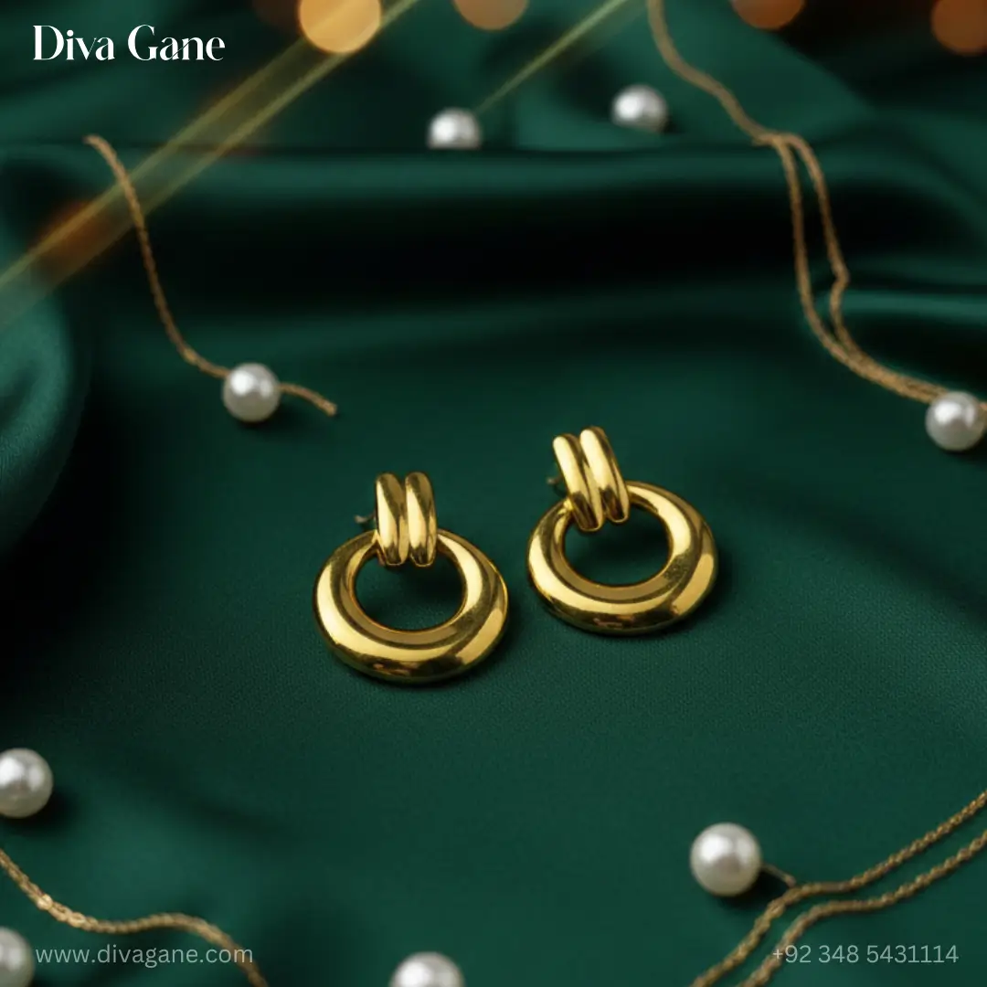 duality dots gold-finished earring. The earring features a thick, polished circular hoop suspended from a double-bar gold post. The background is a dark emerald green silk with warm, out-of-focus golden bokeh lights, creating a luxury aesthetic