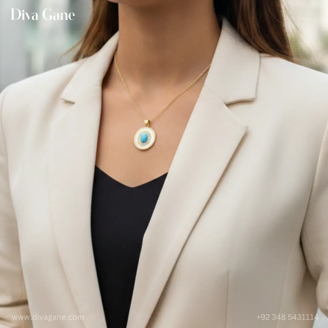 celestial turquoise evil eye medallion – white enamel & gold A professional jewelry photograph of an oval turquoise cabochon pendant surrounded by a sparkling crystal halo and white enamel border, displayed on a marble surface with a teal silk background