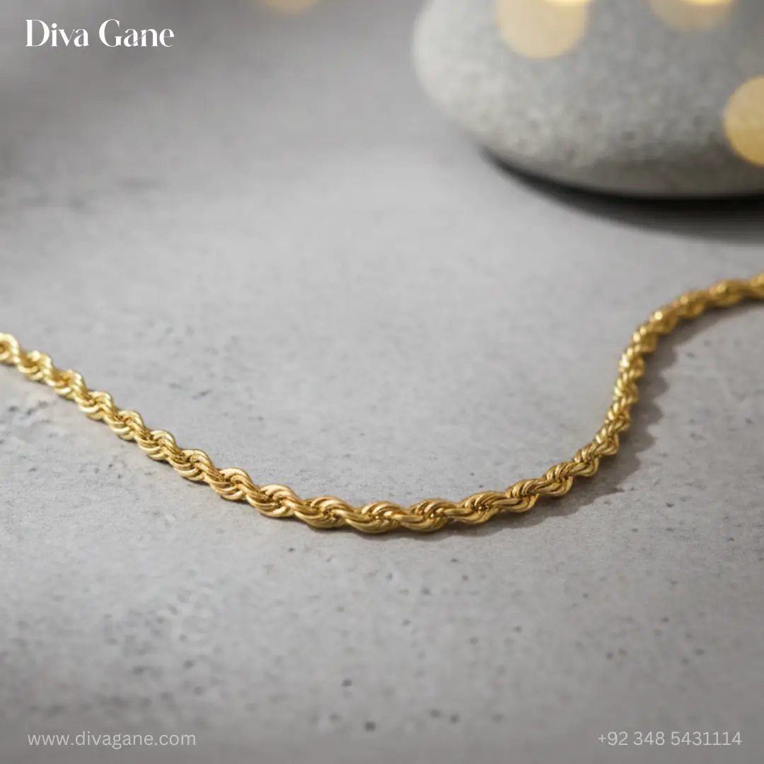 luxe minimalist flat link chain Professional jewelry photography of a gold twisted rope chain displayed on smooth grey river stones with soft eucalyptus leaves and bokeh lighting