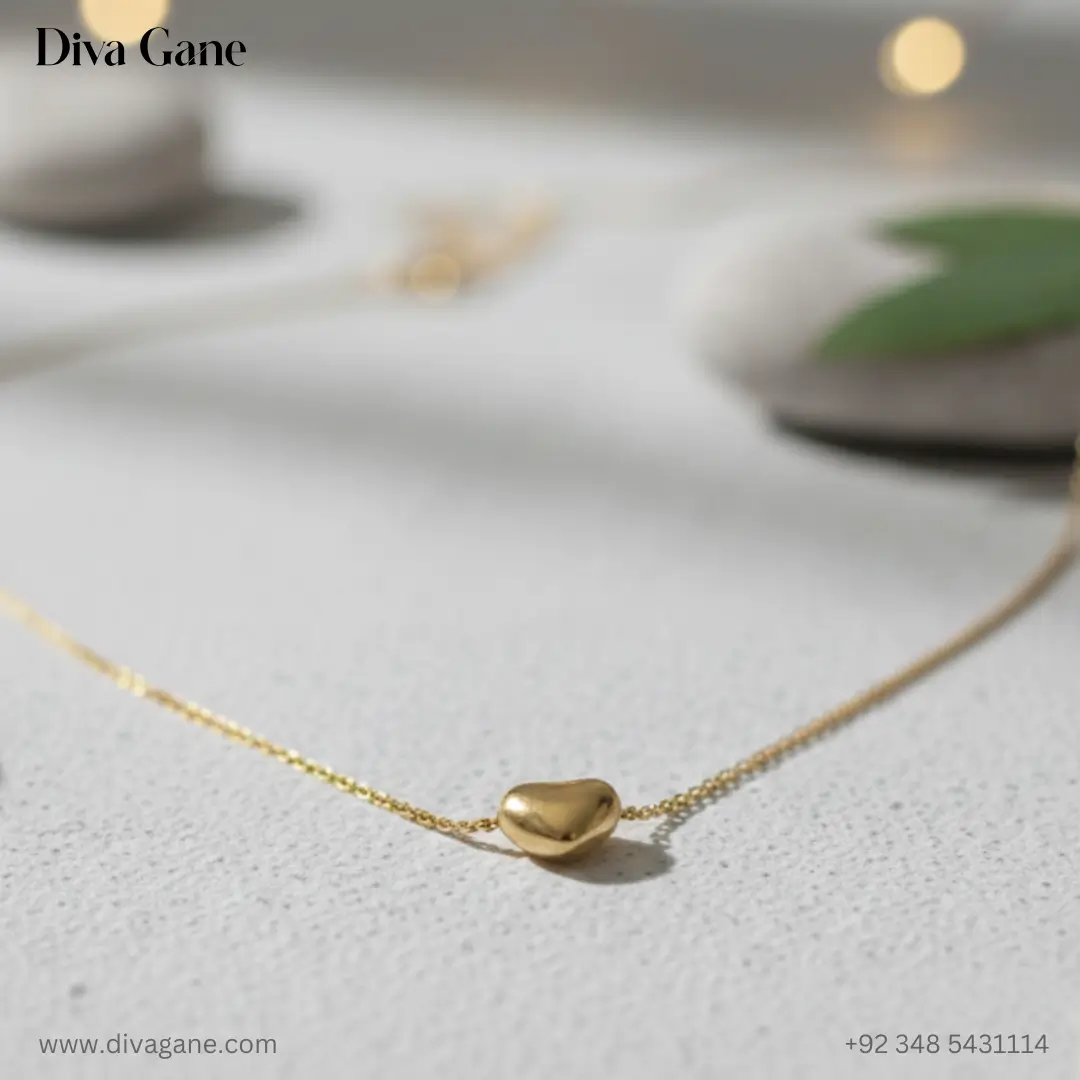 the amora minimalist 3d gold heart charm A macro photograph of a small, polished 3D gold heart pendant on a fine gold chain, resting on a textured white surface with soft bokeh lights