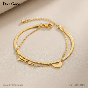 Double-layered gold bracelet featuring a thick flat snake chain and a thin link chain with 'Lover' script and heart charm.