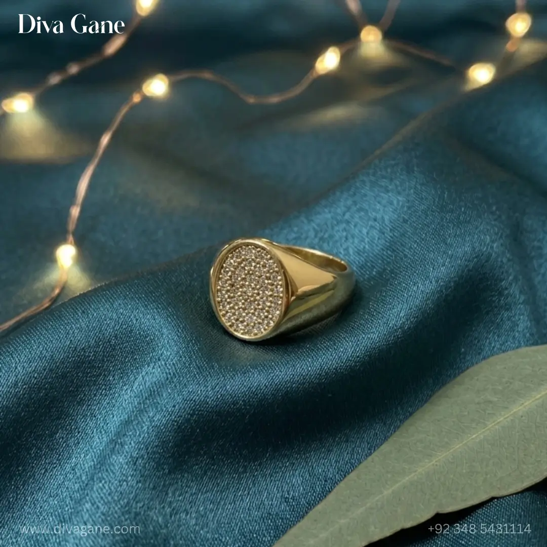 18k gold plated oval pavé signet ring Luxury 18K gold plated oval signet ring with pavé crystal center resting on a dark teal silk cloth background